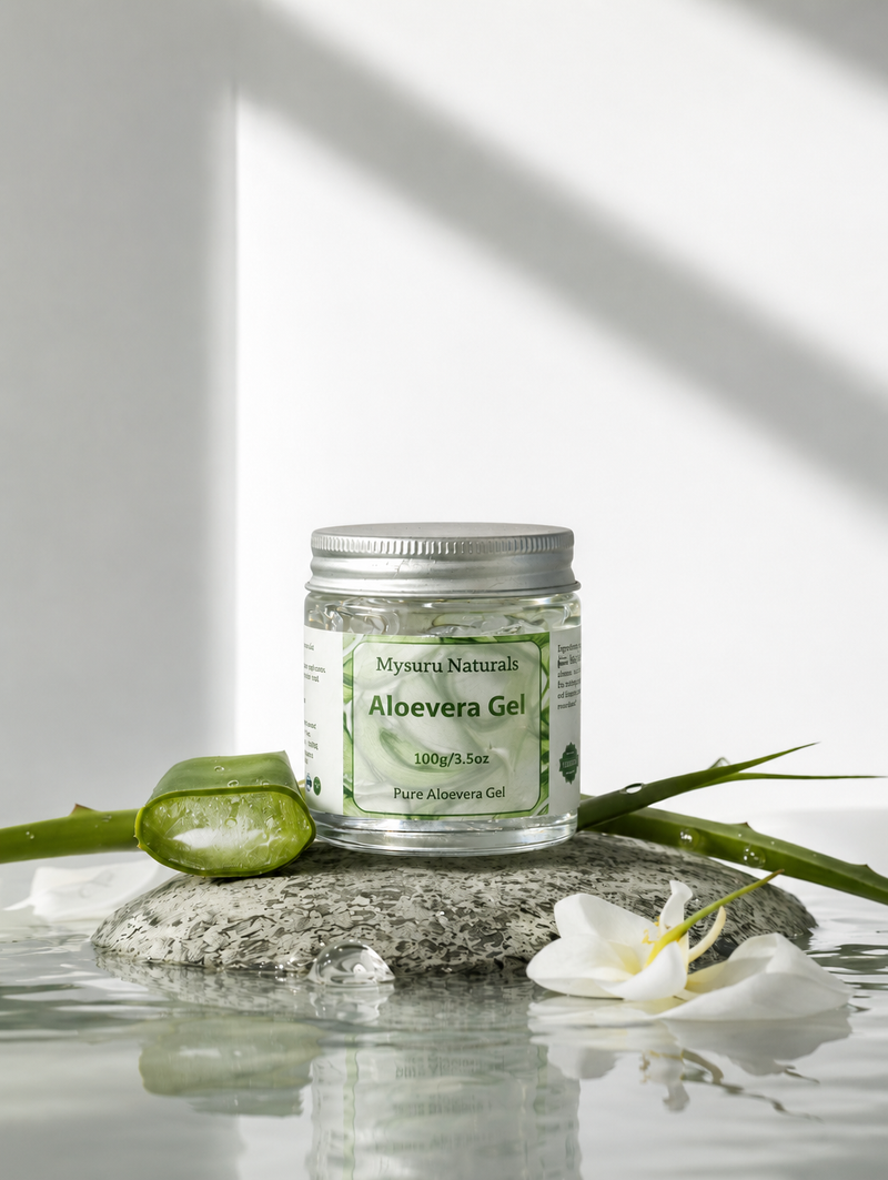 Jar of Mysuru Naturals Aloe vera Gel on a reflective surface with green leaves and a white flower.