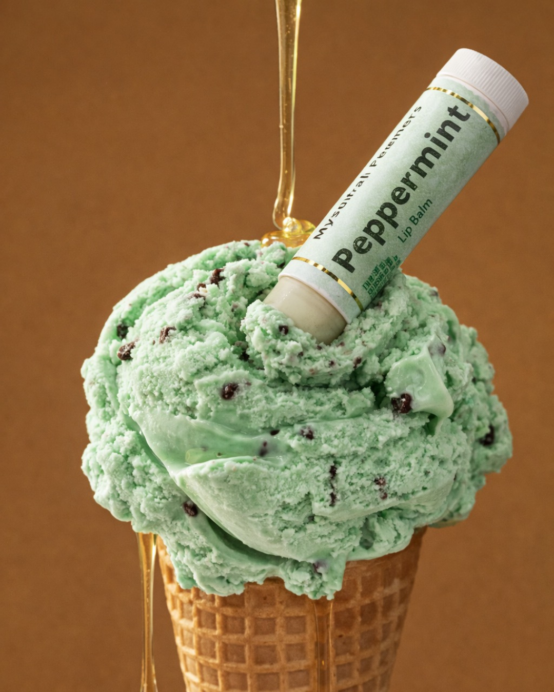 Green ice cream cone with a peppermint lip balm on top against a brown background